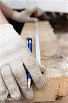 Hands in protective gloves with pen and Metre measure ruler