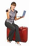 Attractive  girl  sitting on suitcase with laptop on her hands