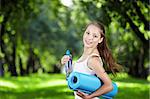 Jeune fille avec une bouteille d'eau et de tapis de gymnastique tourner