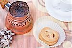 Freshly brewed hot turkish coffee in copper coffee pot with cup, cookies and seashell as decoration