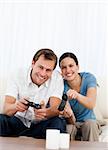 Excited couple playing video games together on the sofa at home