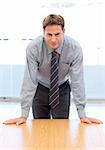 Confident businessman posing leaning on a table in an office