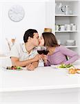 Young couple kissing with red wine in their hands during lunch in the kitchen