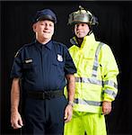 Police officer and firefighter photographed together over a black background.