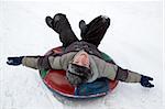 boy sledding down a snowy hill on a color inflatable sled