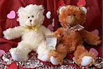Two teddy bears with an engagement ring surrounded by loose diamonds and heart shapes from a romantic propsal.