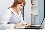 attractive young woman working with laptop on a background of office interior
