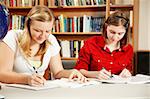 Two high school students doing their homework in the library.