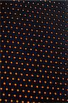 Black plastic mesh texture backlit with orange light.
