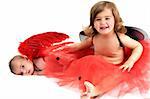 two sisters playing and smiling in studio wearing red angle wings