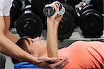 A girl's trainer shows her the correct form of exercise with dumbbell