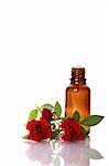 Bottles of essential oil and red rose with beautiful reflection