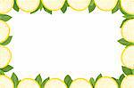 frame made of yellow lemon slices and green leaves on white background