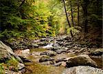 Long duration image of water flowing over boulders and mossy rocks in autumn