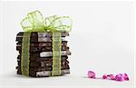 Decorative Stack of Chocolate with green ribbon and small pink flowers isolated on white