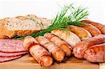 Grilled sausages on a wooden plate with bread and dill