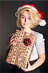 Cute girl in a Christmas hat with a gift box on black background