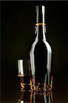 A bottle and a glass of cognac in a black background