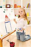 Little smiling artist girl painting her dream house on a large paper canvas