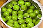 Open metallic tin can with green peas