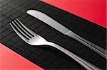 knife and fork on the on black table red napkins by the sides of the flatware