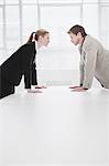 Rival business people leaning over desk