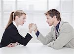 Rival business people arm wrestling