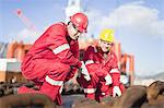 Workers on oil rig examining chains