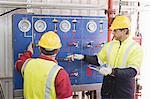 Workers checking gauges on oil rig