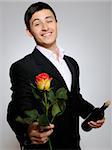 Handsome romantic young man holding rose flower and vine bottle  prepared for a date. focus on rose