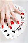 Beautiful hands with perfect red manicure holding a deck of playing cards