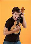 Hispanic teen plays a ukulele with tongue sticking out