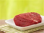 fresh raw meat on white plate and green background