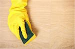 A picture of a hand in yellow gloves cleaning the floor