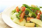 Fresh salad with cucumber, tomato, peppers, baby sweet corn and broccoli on white plate