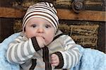 Cute baby boy sitting in a basket against an antique trunk