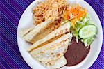 quesadillas rice salad frijoles sauce Mexican food on blue serape