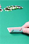 poker player with two aces and chips on a green table