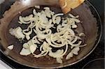 frying sliced white onions in an old pan