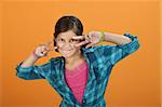 Latina child on an orange background making hand gesture