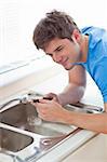 Assertive man repairing his sink in the kitchen at home