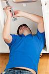 Positive man repairing his sink in the kitchen at home