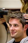 Female hairdresser drying her male customer's hair in her hairdressing salon