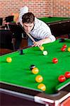 Concentrated young man playing snooker in a club