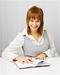 Attractive girl in a white blouse with a notepad and pen on the background of blinds