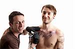 a tattoo artist and his customer during a tattoo session smiling into the camera