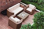 Home exterior patio with wooden decking and rattan sofa view from the top.