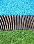 wood floor and fresh grass beside the blue swimming pool