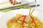 Fettuccine with chicken, mushrooms, red bell pepper and bacon appetizer, cutlery, wine glass in the background (Selective Focus, Focus on Front)