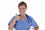 A attractive female nurse with a friendly smile displaying a thumb up, isolated on a solid white background.